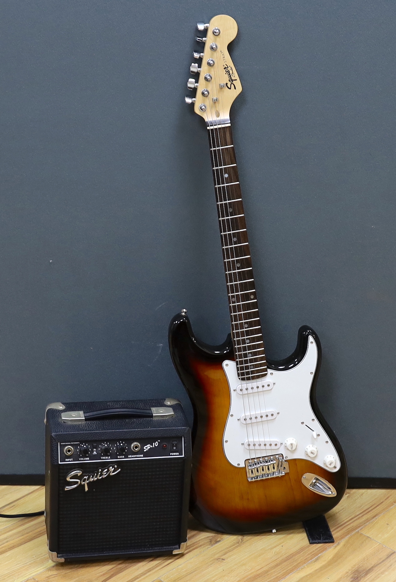 A Squier Strat by Fender Sunburst electric guitar made in China with rosewood neck, together with a small Squire SP-10 amp